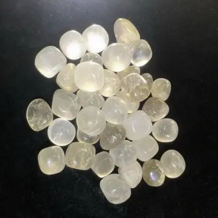 A bulk collection of Clear Quartz Tumbled & Polished Natural Healing Crystals Stones in various sizes, displayed on a rustic wooden tray with a soft - gray linen background.