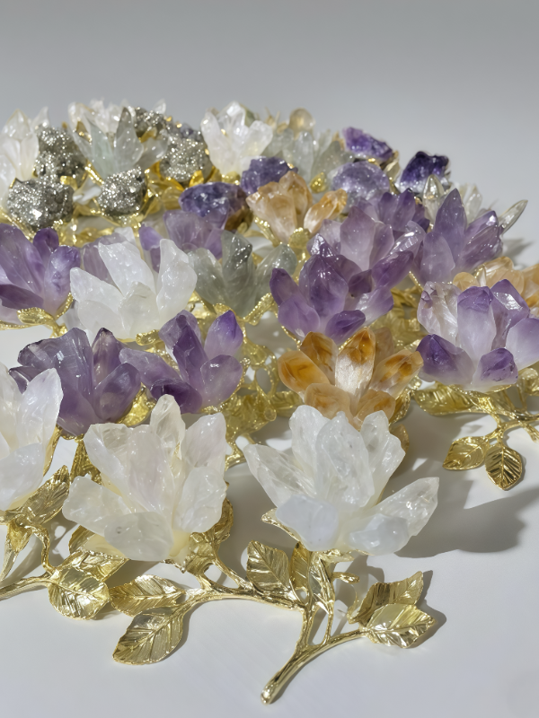 Amethyst crystal lotus flower with gold - plated stem and leaves held in a hand