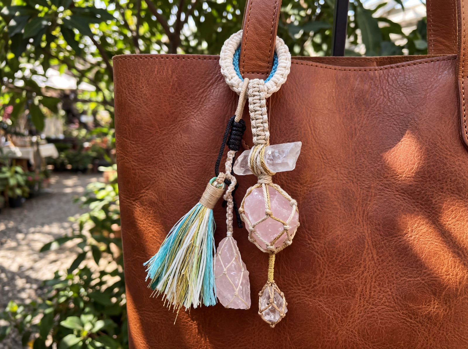 Irregular raw rose quartz and clear quartz chunks inside a hand-knotted macrame bag charm.