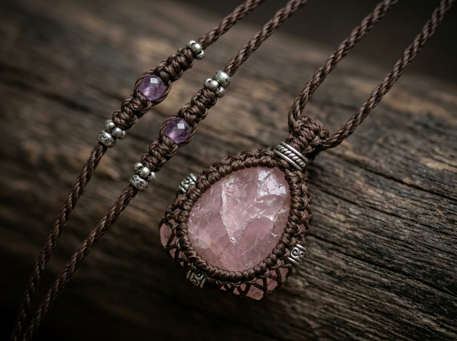 Artisan macrame necklace featuring a large raw rose quartz pendant and small amethyst accent beads on a dark brown wax cord.